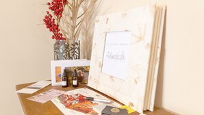Une table avec un vase rempli de baies rouges, une bouteille et des documents imprimés.