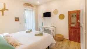 Une chambre à coucher comprenant un lit, un bureau, une télévision et une armoire en bois.