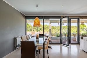 Un comedor con mesa de vidrio, sillas y una lámpara colgante.