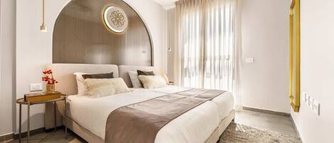 A modern bedroom with a large bed, a bedside table, a decorative wall panel, and a window with curtains.