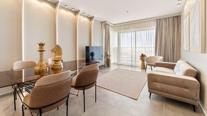 A modern living room with a glass dining table, two sofas, and a TV.
