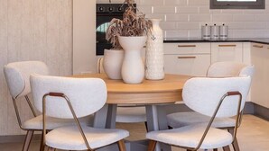 Une cuisine moderne avec une table de salle à manger ronde, des chaises blanches et deux lampes suspendues.