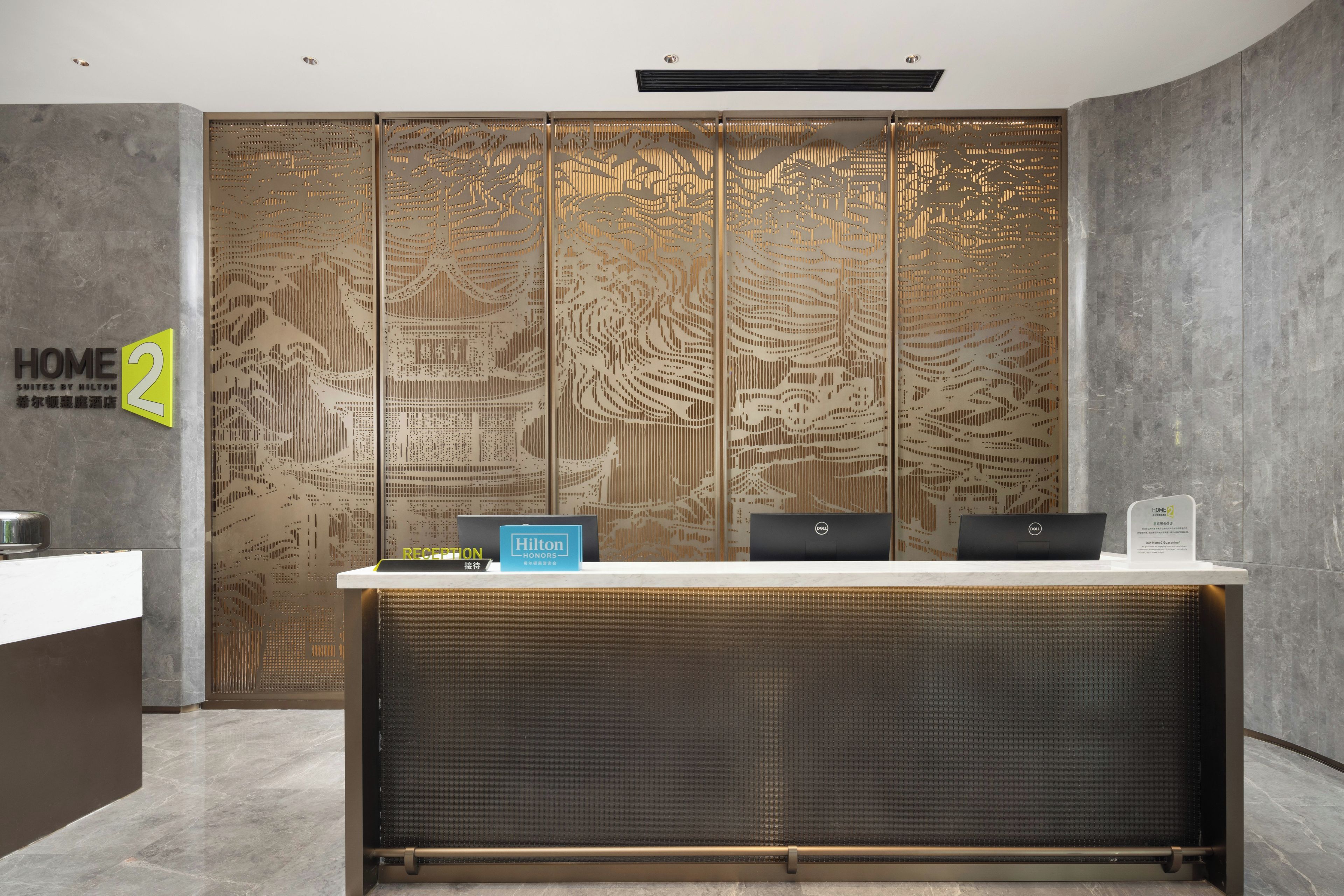 Un comptoir d’accueil au design moderne, une enseigne indiquant « Hilton Honors » et une autre indiquant « Réception ».