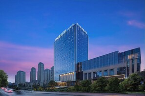 Un edifici d'hotel modern amb una façana de vidre destacada i un terrat pla.