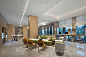 A modern interior with seating areas, tables, and a reception desk.