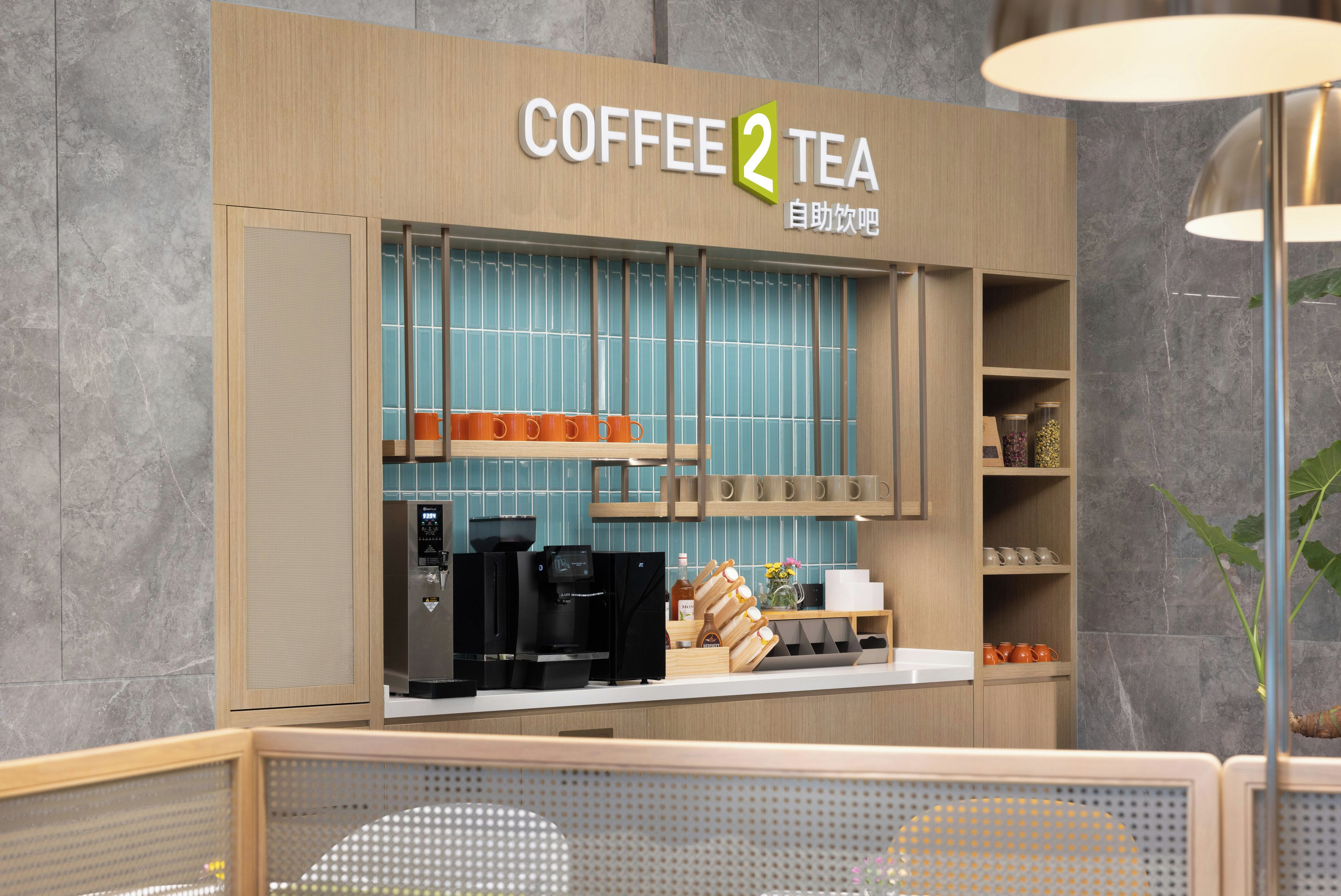 A coffee and tea shop with a modern design, featuring a coffee machine, tea kettles, and a variety of mugs and cups displayed on shelves.