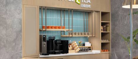 A coffee and tea shop with a modern design, featuring a coffee machine, tea kettles, and a variety of mugs and cups displayed on shelves.