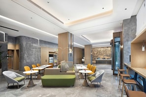 A modern lobby with seating areas, a reception desk, and a vending machine.