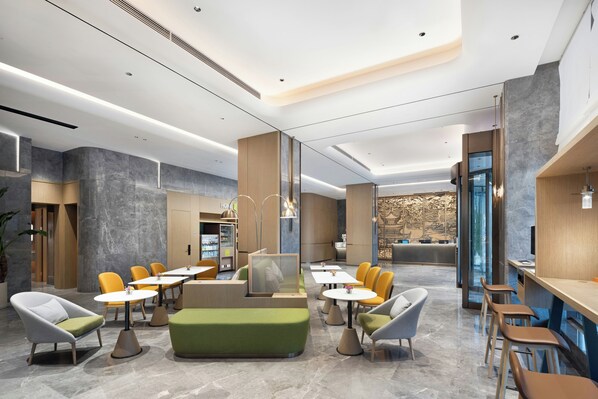 A modern lobby with seating areas, a reception desk, and a vending machine.