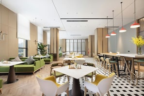 A modern dining area with green sofas, white tables, and yellow chairs.