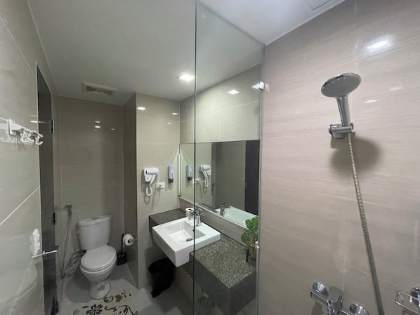 Un baño moderno con ducha de mampara de vidrio, inodoro blanco y lavamanos con espejo.