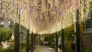 En inomhusgång med hängande blomsterdekorationer och pelare av sten.