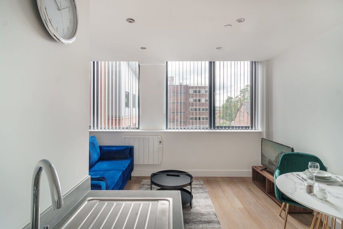 A modern apartment with a kitchen, dining area, and a large window with blinds.
