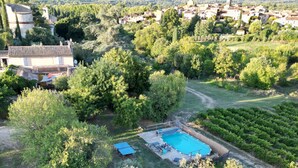 An aerial view of a residential area with a swimming pool, surrounded by lush greenery and houses.