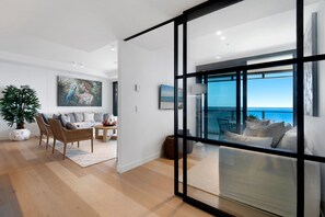 A modern interior with a view of the sea, a dining area, and a living space with a large window. - Jewel Stunning Ocean Views 2 Bed Apartment (Surfers Paradise)