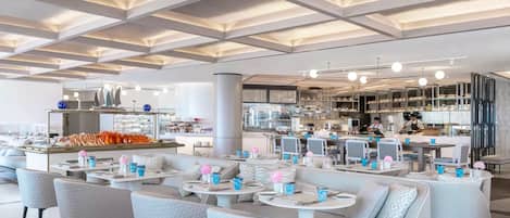 Un restaurante moderno con techo alto, zonas de estar y cocina a la vista.