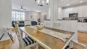Una cocina moderna con armarios blancos, una mesa de comedor de madera y una araña.