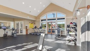 Un gimnasio espacioso con máquinas de cardio, estaciones de pesas y un amplio ventanal que proporciona luz natural.
