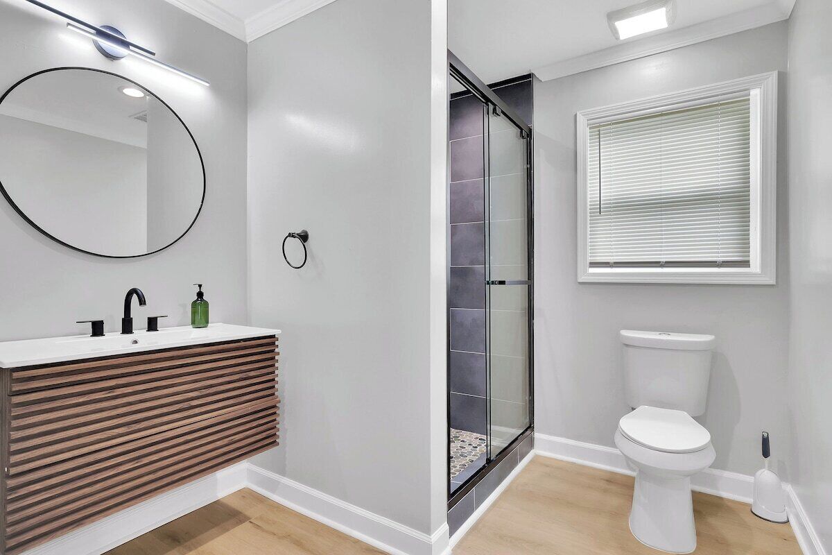A modern bathroom with a wooden vanity, a glass shower enclosure, and a toilet.
