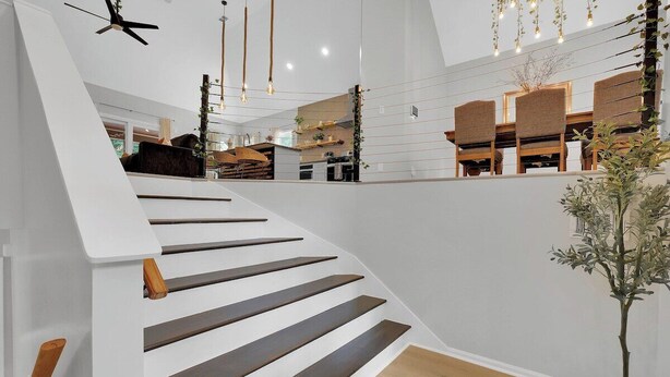 A modern staircase with wooden steps and a white wall. - Beautifully decorated and spacious home with a pool. (Rex)