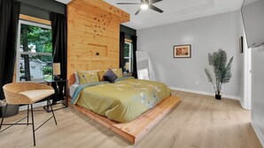 A modern bedroom with a bed, a chair, a ceiling fan, a window, and a plant. - Beautifully decorated and spacious home with a pool. (Rex)