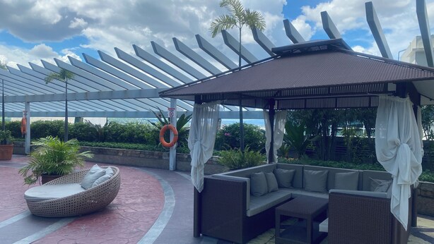 A covered outdoor seating area with wicker furniture and a pergola structure. - Discounted | Elegant 2BR, 2 BA Suite Beside Eastwood Mall (Quezon City)