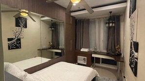 A hotel room with two beds, a desk, a ceiling fan, and a large mirror. - Discounted | Elegant 2BR, 2 BA Suite Beside Eastwood Mall (Quezon City)
