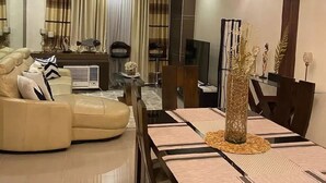 A modern living room with a sofa, dining table, and decorative items. - Discounted | Elegant 2BR, 2 BA Suite Beside Eastwood Mall (Quezon City)