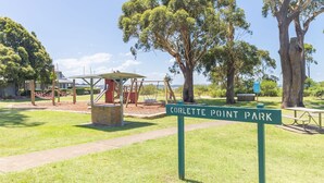 Un parc doté d’une aire de jeux, de tables de pique-nique et d’un panneau indiquant « Parc de Corlette Point ».