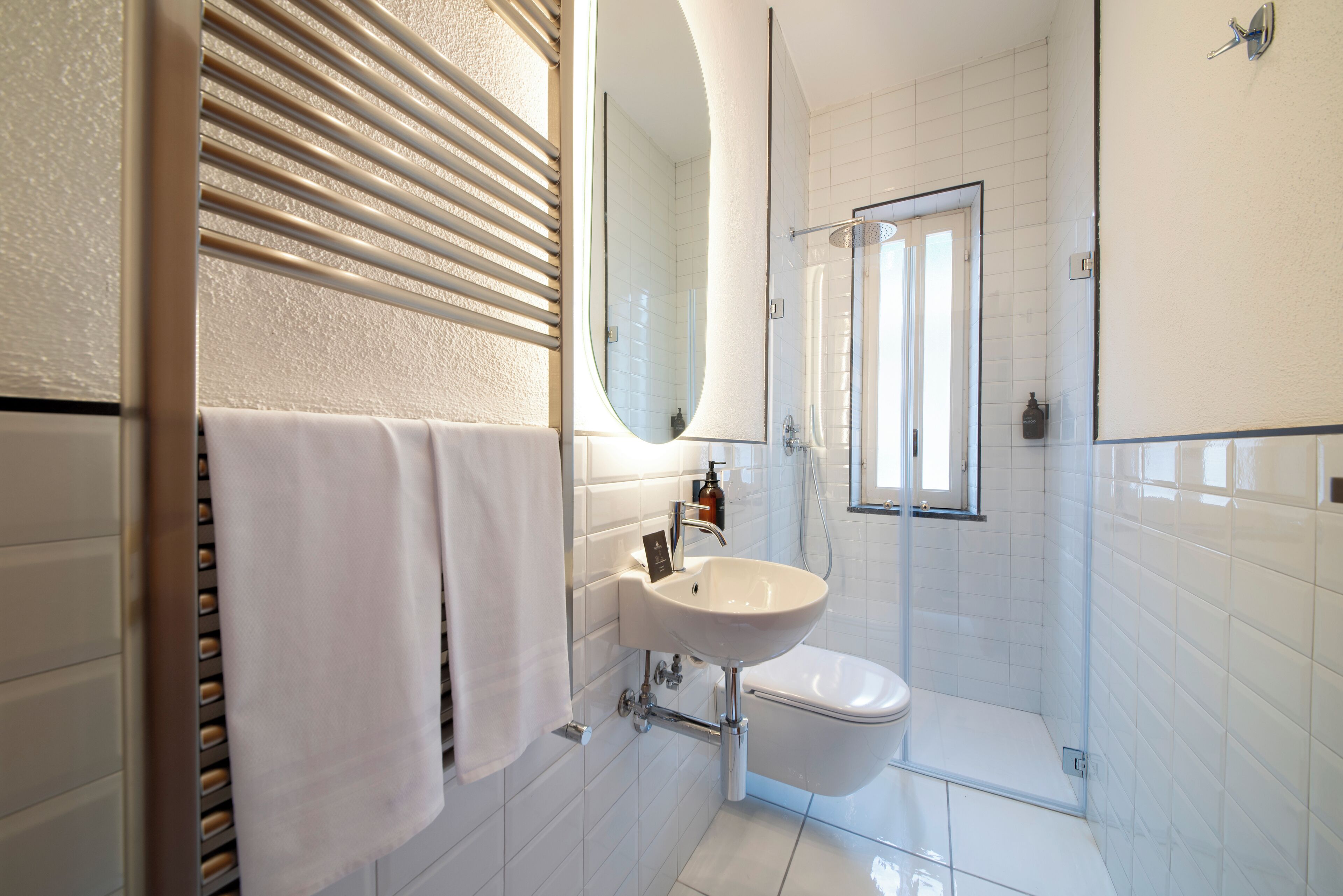 Un bagno moderno con lavandino bianco, uno specchio e una doccia.