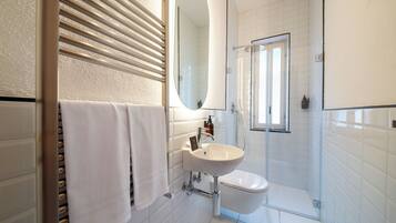 Un bagno moderno con lavandino bianco, uno specchio e una doccia.