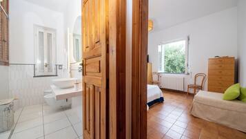 A modern bathroom with a white sink, wooden door, and a window providing natural light.