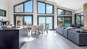 Een moderne keuken met grote ramen, een eethoek en een zithoek met uitzicht op zee.