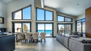Een ruime woonkamer met een groot raam met uitzicht op de oceaan, een moderne keuken met een eethoek, en een gezellige zithoek met uitzicht.