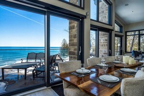Un comedor con vistas al océano, una pared de piedra y un ventanal grande.