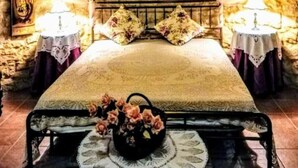 A stone-walled room with a bed, two bedside tables, and a decorative basket on the floor. - Torre Rodosta  (Modica)
