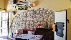 A dining area with a stone wall, wooden ceiling, and a table with floral tablecloths. - Torre Rodosta  (Modica)