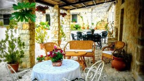 A covered outdoor seating area with wicker furniture and a table with a lace tablecloth. - Torre Rodosta  (Modica)
