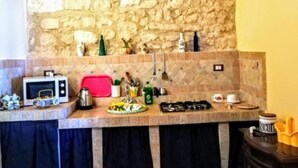 Una cocina con pared de piedra, microondas, cocina a gas y pileta.