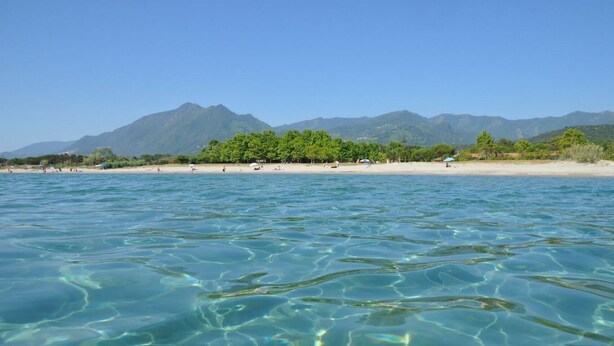 A beach with clear water, a sandy shore, and a mountain range in the background. - Villa Moderne Avec Jardin à 300 m du Bord de mer (Santa-Lucia-di-Moriani)
