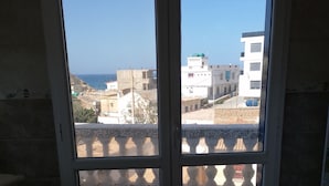A room with a view of buildings and the sea through a glass door. - Bouzedjar-mer (Bou Zadjar)