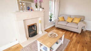 A living room with a fireplace, a sofa, a table, and a mirror. - 12 Hillview (Buncrana)