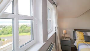 A bedroom with a view of a green landscape and a body of water. - 12 Hillview (Buncrana)