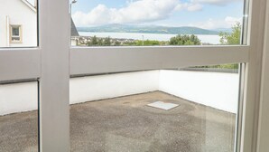 A balcony with a view of a lake and mountains, a white building, and a clear sky. - 12 Hillview (Buncrana)