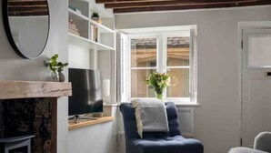 A cozy living room with a television, a blue armchair, and a fireplace.
