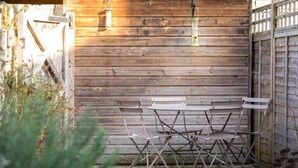 A rustic wooden wall with a metal table and chairs in front.