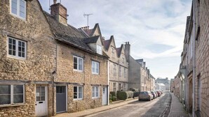 A narrow street lined with stone buildings, featuring traditional architecture with pitched roofs and chimneys.