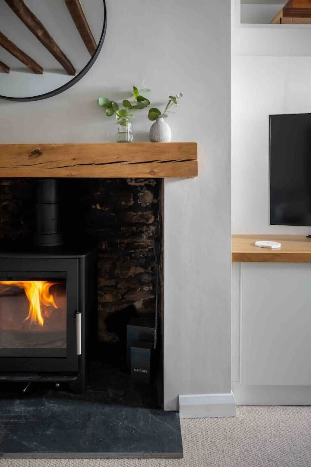 Una sala de estar moderna con una chimenea de piedra, un fuste de madera y un televisor de pantalla plana sobre un mueble.