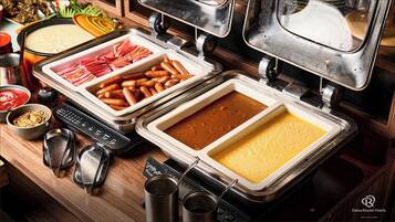 A buffet setup with various dishes including sliced meats, sausages, and a creamy soup.