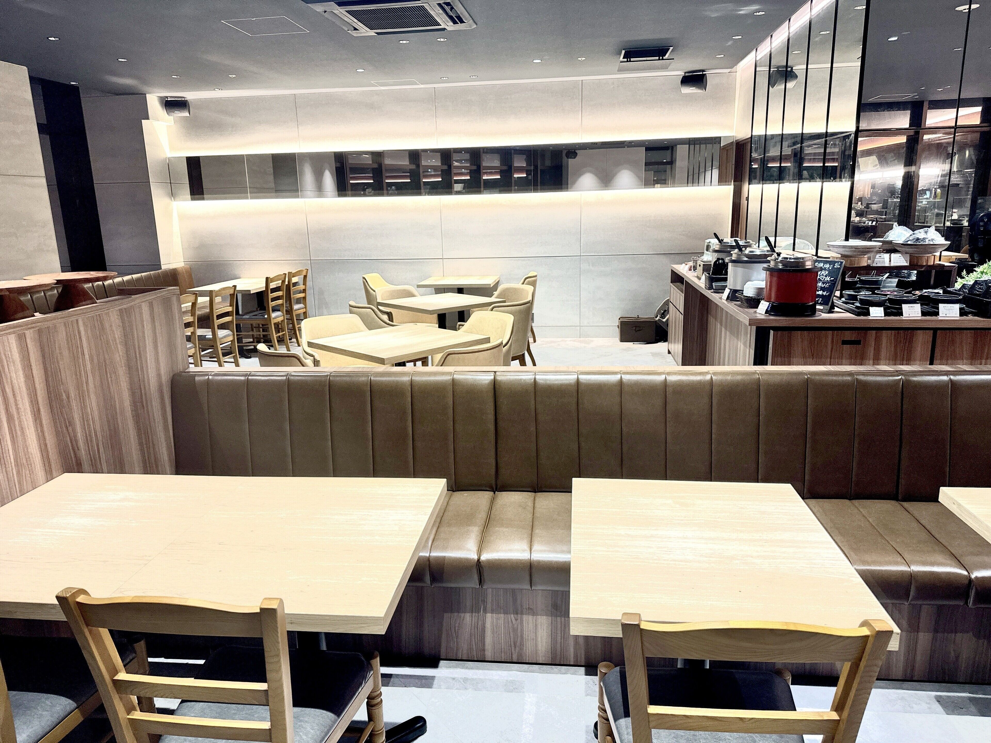 Un interior de restaurante moderno con asientos tipo cabina, mesas de madera y una zona de bar.